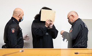 Der Angeklagte (24) hält sich im Saal des Landgerichts eine Aktenmappe vor das Gesicht. Er soll zusammen mit seiner Freundin den Bielefelder Kadir A. mit mehr als 100 Messerstichen getötet haben. - picture alliance/dpa Der Angeklagte (24) hält sich im Saal des Landgerichts eine Aktenmappe vor das Gesicht. Er soll zusammen mit seiner Freundin den Bielefelder Kadir A. mit mehr als 100 Messerstichen getötet haben. - picture alliance/dpa