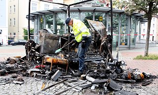 Der Brandexperte Edgar Aust sucht im zerstörten Imbisswagen nach Spuren. Rechts liegt der Stromgenerator. - Jens Reichenbach Der Brandexperte Edgar Aust sucht im zerstörten Imbisswagen nach Spuren. Rechts liegt der Stromgenerator. - Jens Reichenbach