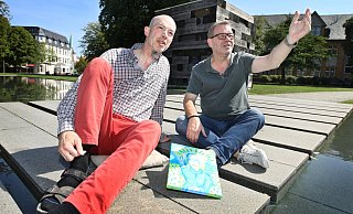 Holger Sauer (l.) hat sein Bild „Jesus mit rosa Lippen" mitgebracht zum Mittagsgespräch mit NW-Kulturchef Stefan Brams. Wegen des schönen Wetters entstand das Foto vorm Holzhaus. - Sarah Jonek Holger Sauer (l.) hat sein Bild „Jesus mit rosa Lippen" mitgebracht zum Mittagsgespräch mit NW-Kulturchef Stefan Brams. Wegen des schönen Wetters entstand das Foto vorm Holzhaus. - Sarah Jonek
