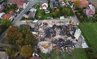 Luftaufnahme der Brandstelle in Hille-Holzhausen: Die Überreste der Holz- und Kunststoffbaufirma zeigen das Ausmaß der Zerstörung nach dem Großbrand. - Alex Lehn Luftaufnahme der Brandstelle in Hille-Holzhausen: Die Überreste der Holz- und Kunststoffbaufirma zeigen das Ausmaß der Zerstörung nach dem Großbrand. - Alex Lehn