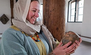 Eine Sächsin (Reenactment-Darstellerin Sally Schönnekess), gekleidet wie im achten Jahrhundert, hält ein Webgewicht, das mit einem Kreuz verziert ist, in ihren Händen. - Huxarium-Gartenpark Höxter/Manuela Puls Eine Sächsin (Reenactment-Darstellerin Sally Schönnekess), gekleidet wie im achten Jahrhundert, hält ein Webgewicht, das mit einem Kreuz verziert ist, in ihren Händen. - Huxarium-Gartenpark Höxter/Manuela Puls