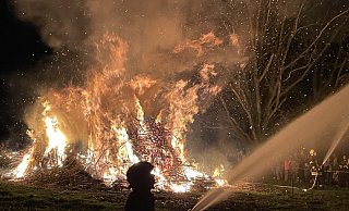 Wenn es auf Dembergs Hof in Bad Oeynhausen-Lohe stockdunkel ist, entzünden die Besucher ein mächtiges Osterfeuer. Damit die Flammen nicht auf die umliegenden Bäume übergreifen, halten Brandbekämpfer Wasserpistolen auf die Äste. - Elke Niedringhaus-Haasper Wenn es auf Dembergs Hof in Bad Oeynhausen-Lohe stockdunkel ist, entzünden die Besucher ein mächtiges Osterfeuer. Damit die Flammen nicht auf die umliegenden Bäume übergreifen, halten Brandbekämpfer Wasserpistolen auf die Äste. - Elke Niedringhaus-Haasper