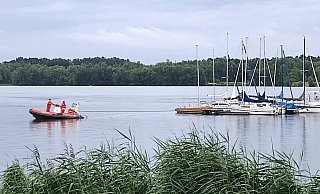 Ein DLRG-Motorboot schleppt den abgetriebenen Steg mit insgesamt acht festgebundenen Booten zurück ans Ufer. - DLRG Ein DLRG-Motorboot schleppt den abgetriebenen Steg mit insgesamt acht festgebundenen Booten zurück ans Ufer. - DLRG